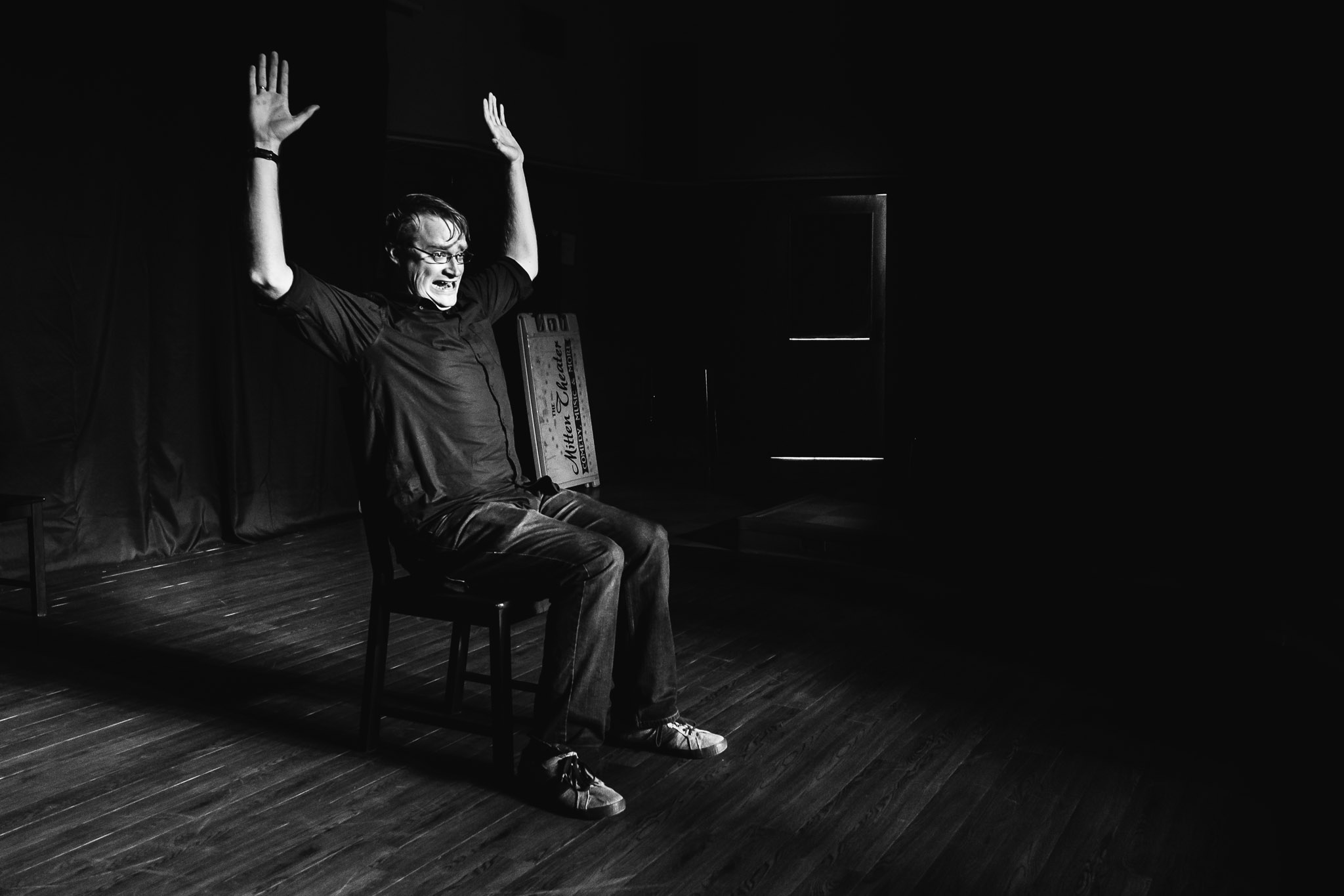 BNW photo of a man sitting in a chair with his arms raised in the air like he is guilty. Guilty of what you ask? Guilty of being a lazy photographer.